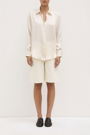 Person wearing a white shirt and beige shorts on a white background