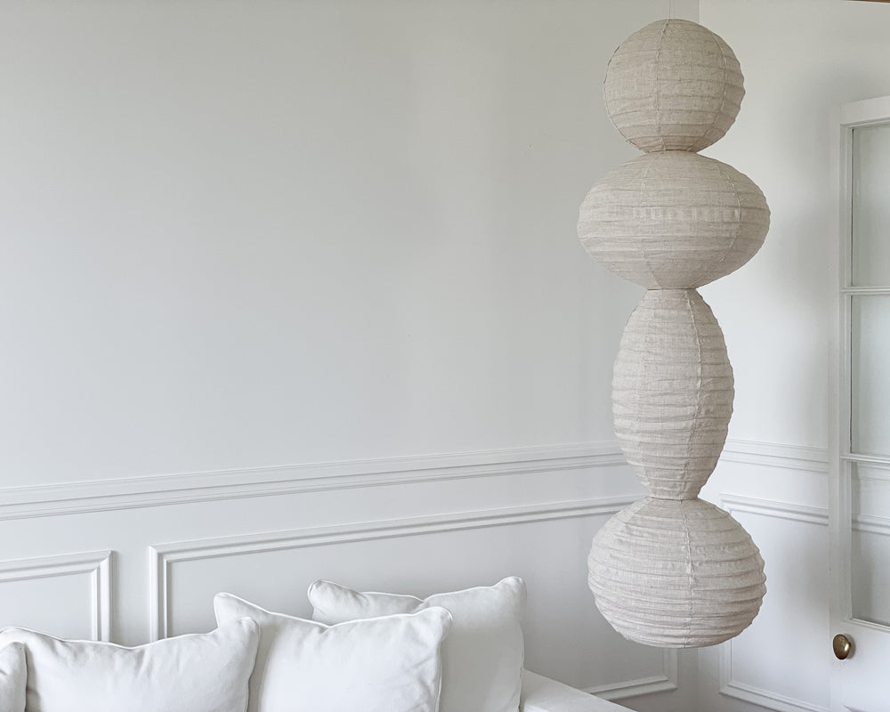 linen light shade composed of 2 sphere and 2 oval shapes connected hung in the corner of a living room room with wainscotting detailing