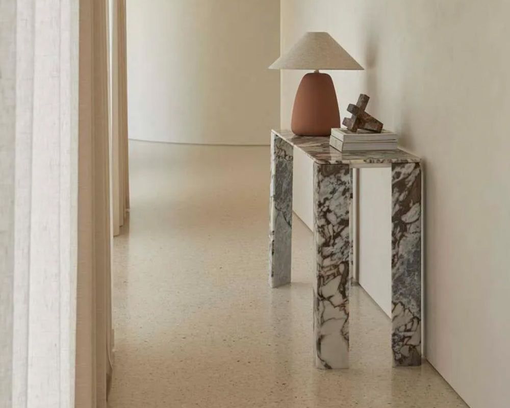 Marble console table with ocean toned veining and sleek design, placed in an entrance hallway.